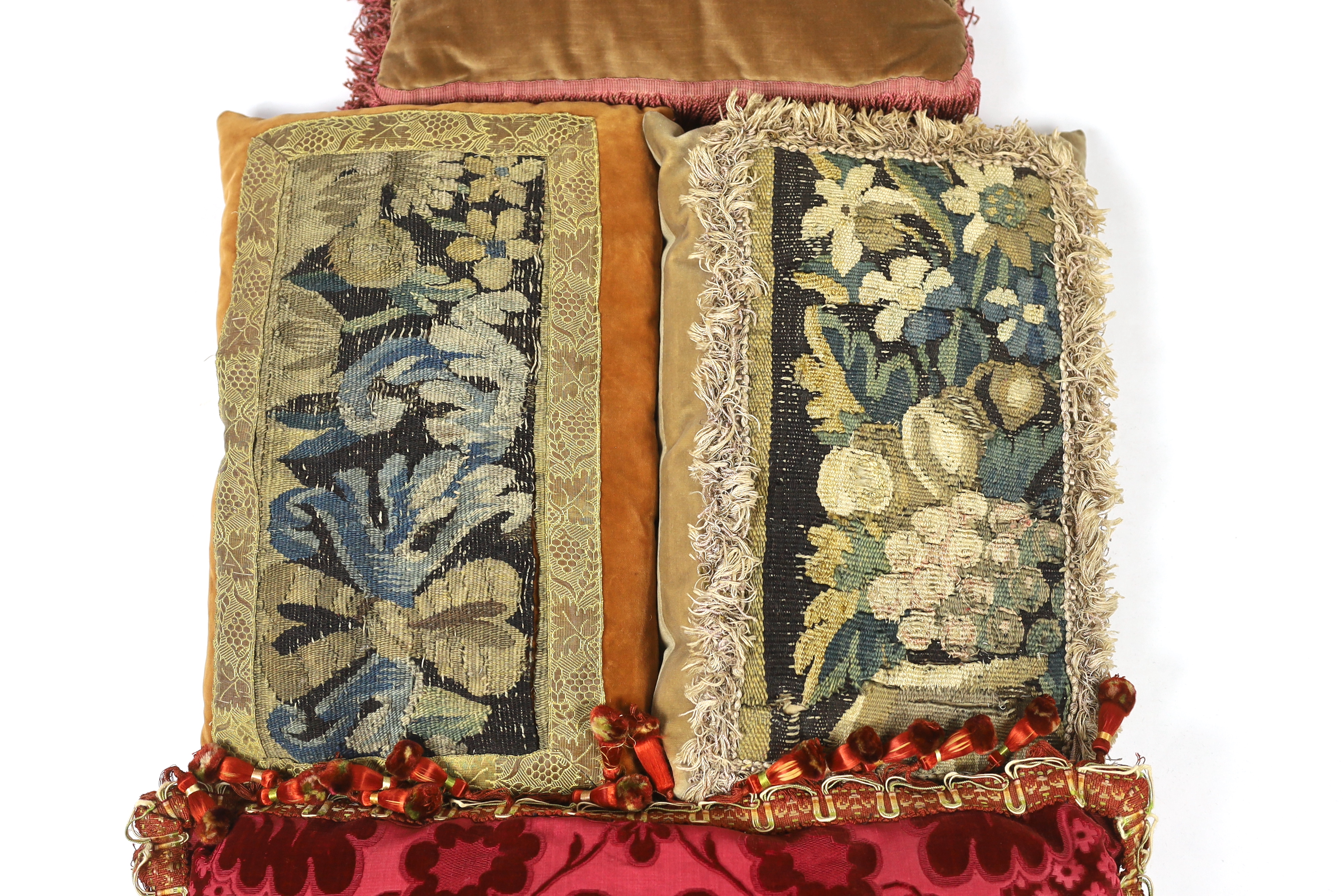 Two late 18th century Flemish verdure tapestry fragments made into cushions, plus a 19th century French Aubusson and an early 19th century Italian burgundy cut velvet damask panel, both made into cushions, all trimmed wi